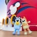 Bluey y Bingo paradas junto a la chimenea de un barco en la cubierta superior de un crucero Disney